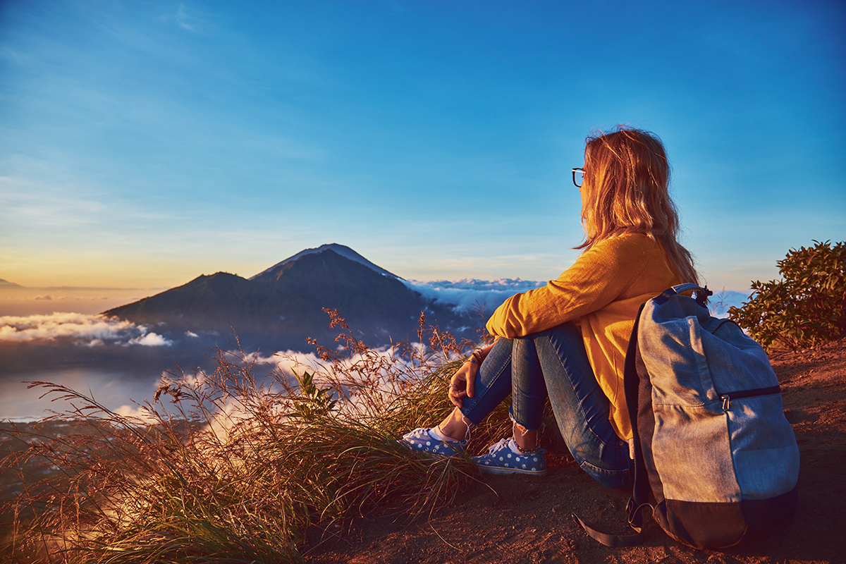 Woman enjoying nice landscape and sunrise from a top of mountain Batur, Bali, Indonesia.